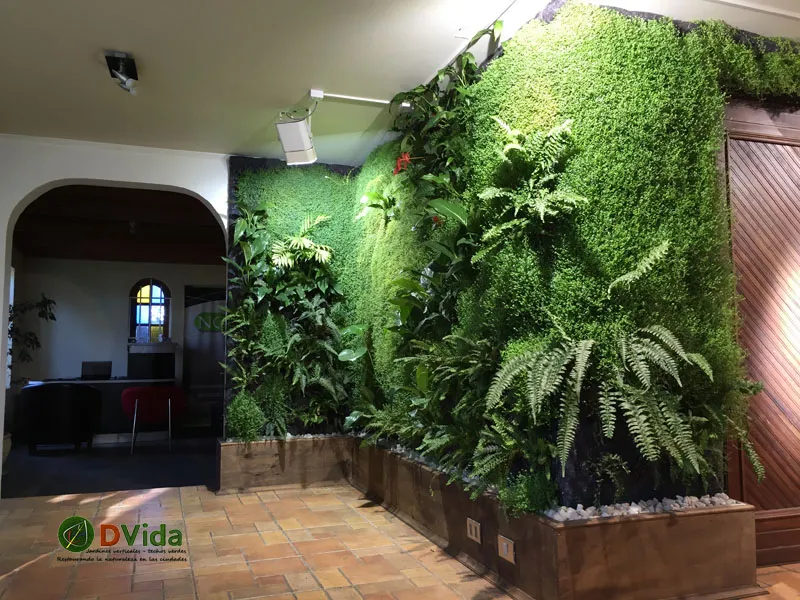 Muro verde interior en esquina con helechos y plantas tropicales